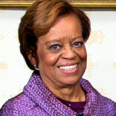 Marian Robinson, Michelle Obama’s mother, smiling, in a purple tweed jacket, in a White House group photograph from January 20, 2013. Cropped.
