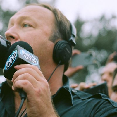 Alex Jones, in headphones, holding a microphone, photographed on November 22, 2013. Cropped. Not from the 2014 broadcast.