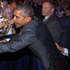 Barack Obama, smiling, shakes hands with an audience member at the Catholic Health Association conference on June 9, 2015. Cropped from an official White House photograph.
